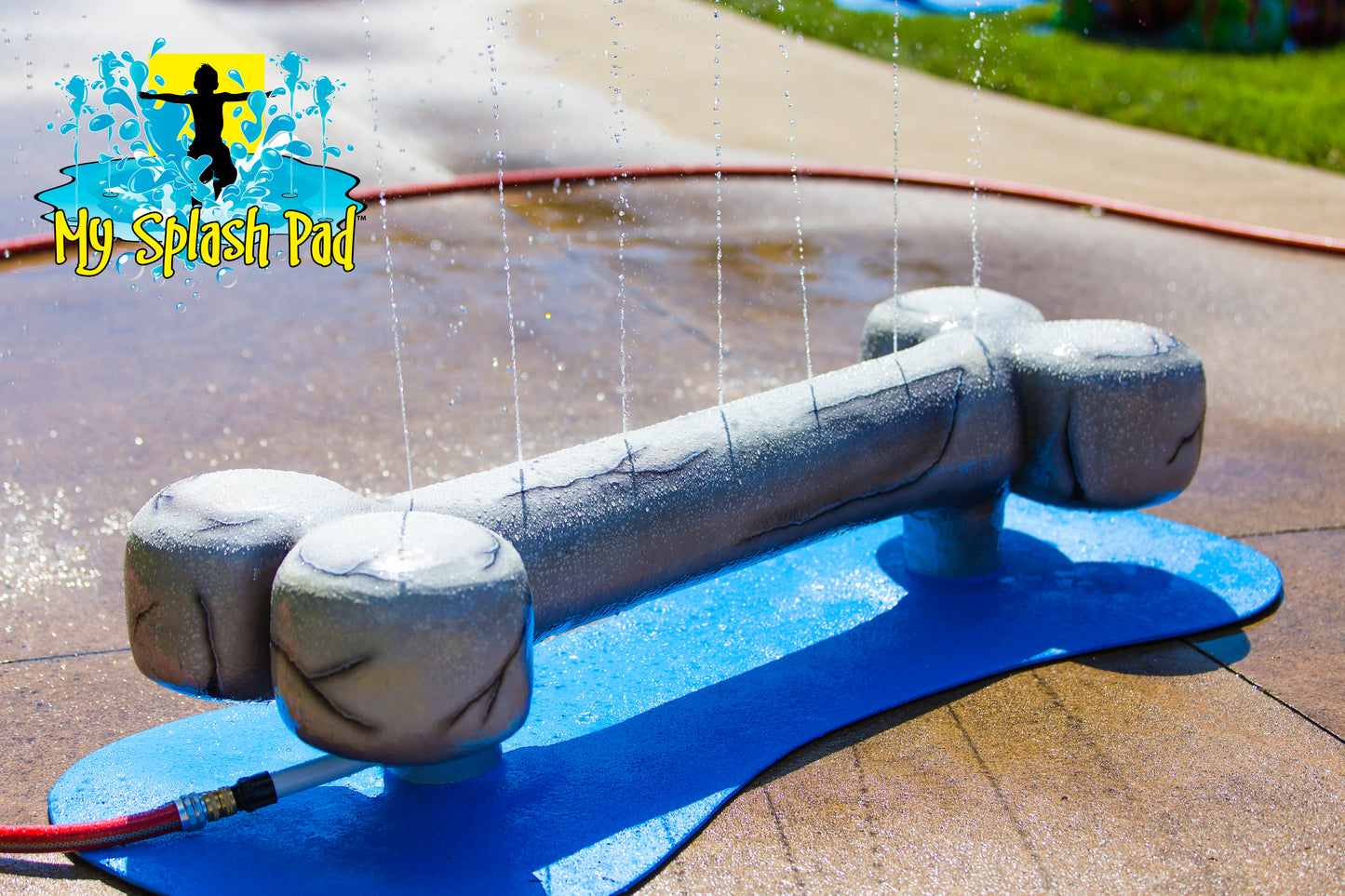 Dog Bone Water Play Feature by My Portable Splash Pad – sculpted gray dog bone splash toy spraying water streams upward, mounted on a blue base for outdoor water play.