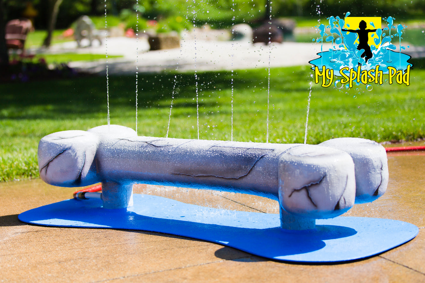 Dog Bone Water Play Feature by My Portable Splash Pad – sculpted gray dog bone splash toy spraying water streams upward, mounted on a blue base for outdoor water play.