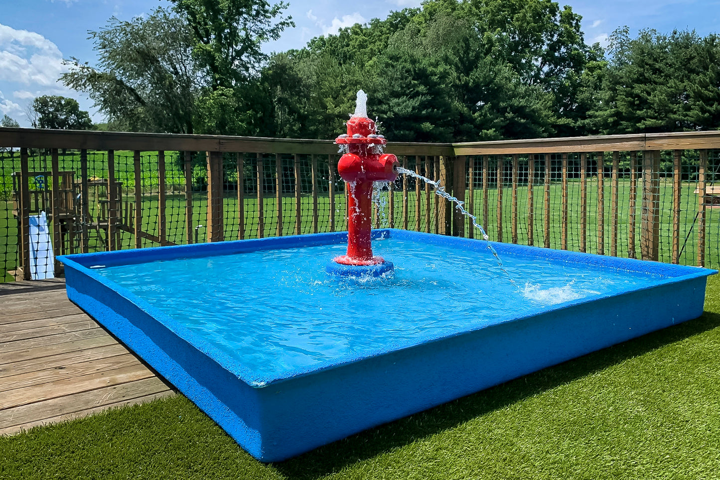 Dog Wading Pool by My Portable Splash Pad – blue rectangular pool with red fire hydrant water play feature spraying streams in backyard setting.